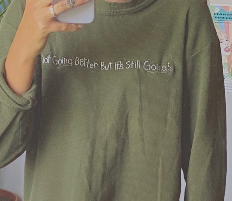 Shirt with embroidered phrase 'It's not going better but it's still going'