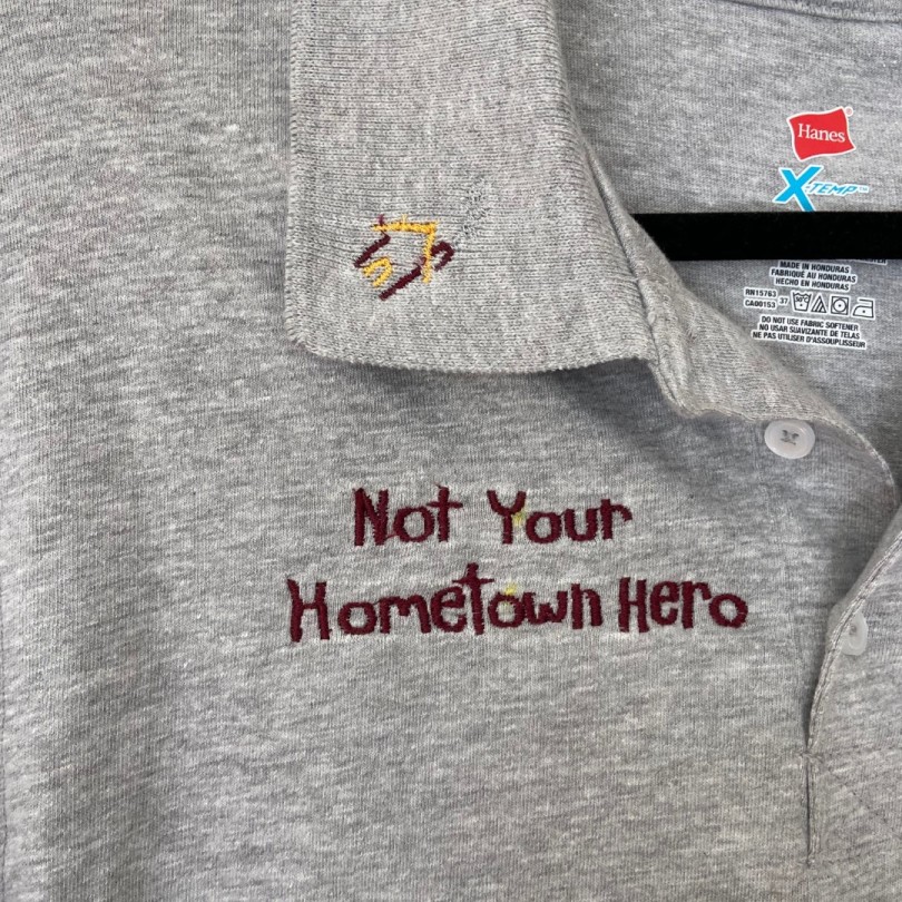 A collared shirt with embroidered phrase 'Not your hometown hero'